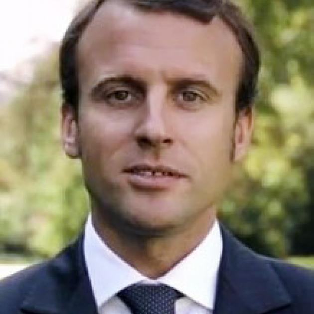 Young looking man with brown hair receding hairline against trees in background