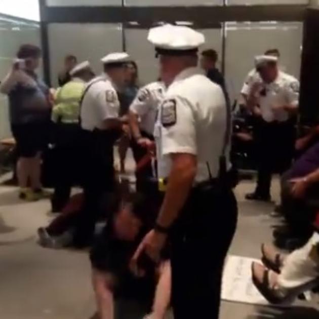 Policeman throwing a woman out of her wheelchair