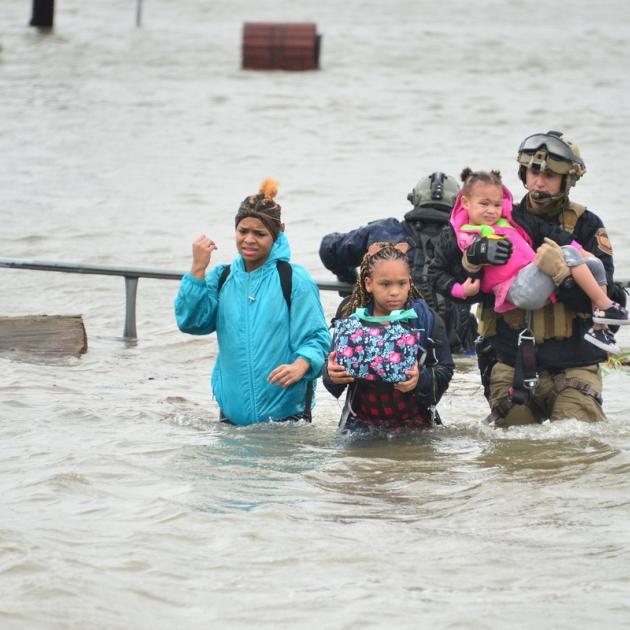 People wading through wasit deep flood